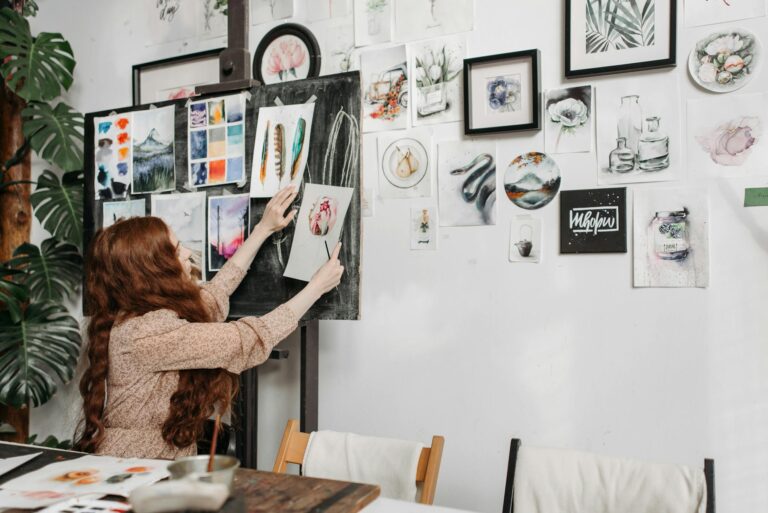 Woman artist organizing colorful paintings on a gallery wall. Creative and inspiring studio environment.